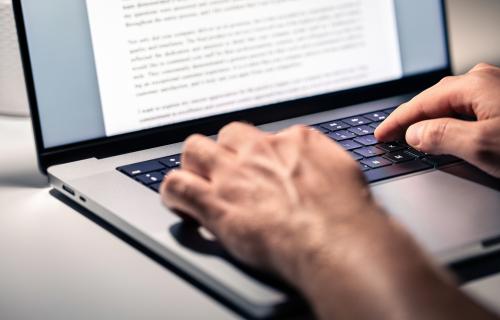 Two hands typing on a laptop keyboard